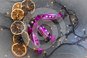 Christmas composition of dried orange and lemon slices with candy toys, garland lights on gray background. Top view, selective