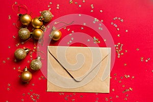 Christmas composition. Envelope, toys on red background with golden confetti. new year concept. Greeting card, xmas celebration