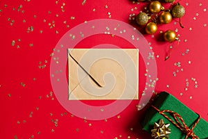 Christmas composition. Envelope, wrapped gift, toys on red background with golden confetti. new year concept. Greeting card, xmas