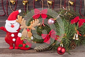 Christmas composition of fir branches decorated with bows and balls Santa Claus reindeer on a wooden background