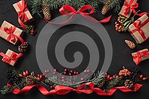 Christmas composition of fir branches, pine cones, berries, gifts and red slack, on black stone background