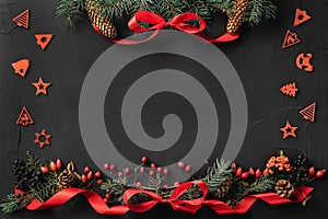 Christmas composition of fir branches, pine cones, berries, gifts and red slack, on black stone background