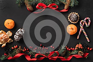 Christmas composition of fir branches, pine cones, berries, gifts and red slack, on black stone background