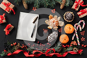 Christmas composition of fir branches, pine cones, berries, gifts and red slack, on black stone background