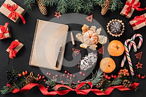 Christmas composition of fir branches, pine cones, berries, gifts and red slack, on black stone background