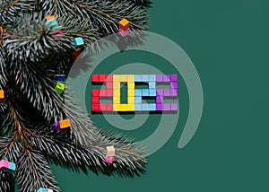 Christmas composition with a fir tree branch and colorful cubes from a children's constructor. Namber 2022 from magnet