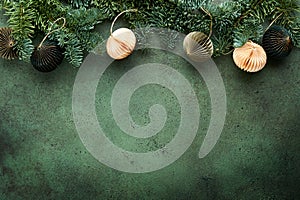 Christmas composition. Christmas fir tree branches with pine cones and papers rustic balls on old green concrete rustic background