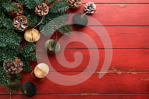 Christmas composition. Christmas fir tree branches with pine cones and papers rustic balls on wooden red rustic background.