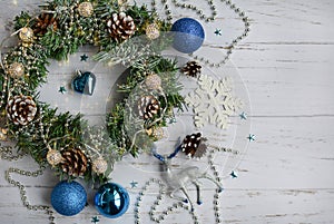 Christmas composition of fir wreath, blue balls, cones, snowflakes on a light wooden table
