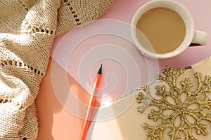 Christmas composition, Flat lay with cup of coffee  warm plaid book and pencil.  Sunset light and shadows. At home