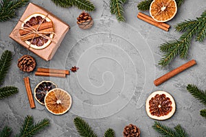 Christmas composition. Gift box, cinnamon, anise, dried fruits, pine cones and fir needles decorations on grey background