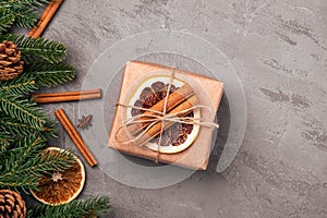 Christmas composition. Gift box, cinnamon, anise, dried fruits, pine cones and fir needles decorations on grey background