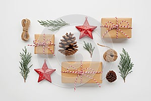 Christmas composition with gift boxes wrapped in craft paper, pine cones, conifer branches, decorative toys on white background