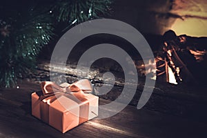 Christmas composition, gift under the tree near a burning fireplace, close-up