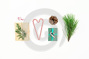 Christmas composition of gifts with candy cane, pine branch and cone on white background. New year concept. Flat lay
