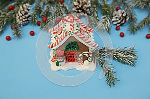 Christmas composition gingerbread house on the blue background of a winter spruce. Close-up. The concept of Christmas and New Yea