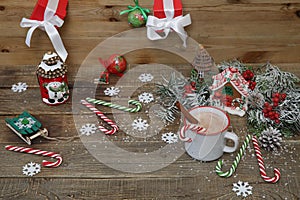 Christmas composition with gingerbread house, mug of chocolate cocoa, caramel sugar canes and decorations on wooden background