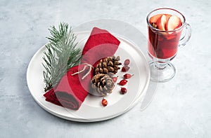 Christmas composition with a glass of mulled wine and a beautifully decorated plate with spruce branches and a red