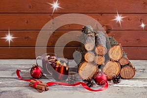 Christmas composition. Glasses of mulled wine, christmas balls, cinnamon, pine cones and pile of firewood