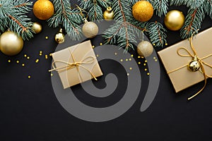 Christmas composition. Golden baubles, modern festive decorations, gift boxes, fir tree branches on dark black background. Elegant