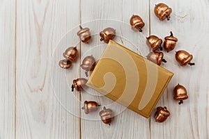 Christmas composition.Golden present box and golden acorns.White wooden table