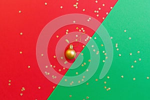 Christmas composition. Golden toy on red and green background with golden confetti. new year concept. Greeting card, xmas