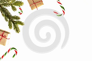 Christmas composition. Green fir twings, Xmas gifts and candy canes on white background. Top view, flat lay. Copy space