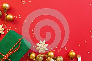 Christmas composition. Green gift box, golden toys on red background with golden confetti. new year concept. Greeting card, xmas