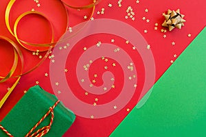 Christmas composition. Green gift box on red and green background with golden confetti. new year concept. Greeting card, xmas