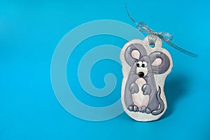 Handmade gingerbread in the form of a funny gray rat with a silver bow on a light blue background. Christmas, winter, New year.