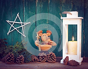 Christmas composition of a homemade star, a toy moose, a lantern with a candle,