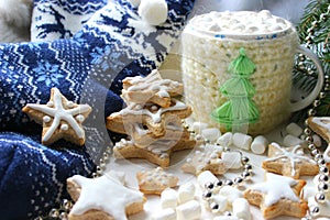 Christmas composition. Hot cocoa with marshmallows in knitted Cup, scattered ginger cookies in glaze on a white background