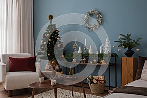 Christmas composition in the living room interior with beautiful decoration, white armchair, christmas tree, balls, console,