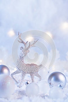 Christmas composition made of Christmas balls and figurine of reindeer on blue winter background. Minimal styled holiday card.