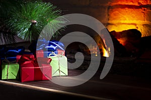 Christmas composition, many colorful gifts under the tree near the burning fireplace, close-up