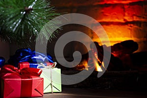 Christmas composition, many colorful gifts under the tree near the burning fireplace, close-up