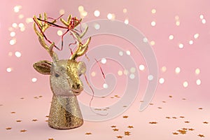 Christmas composition in minimal style - golden deer head on pink background with New Year lights, copy space