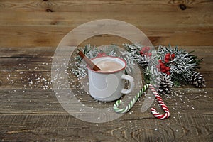 Christmas composition with mug of cocoa, caramel canes and decorations on wooden background with copy space for text.