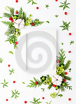 Christmas composition  with photo frame, cotton flower, branches of spruce and holly with red berries on white background. Merry