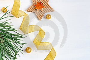 Christmas composition of pine branches, golden balls, ribbons and stars on white wooden background