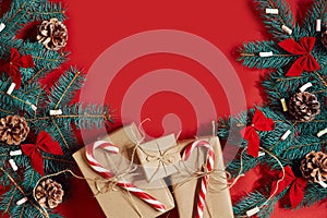 Christmas composition of pine cones, spruce branches and stack of gift boxes on red background