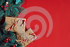 Christmas composition of pine cones, spruce branches and stack of gift boxes on red background