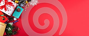 Christmas composition on a red background, a border of gift wrapping, cones and ribbons, top view and copy space