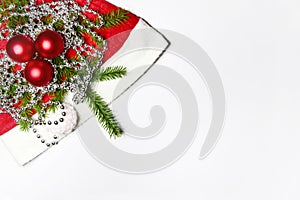 Christmas composition red Christmas balls and a spruce branch on Santa`s hat with shiny beads on a light background. Copy space.