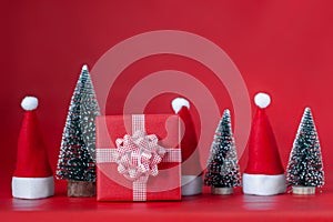 Christmas Composition with red present box and christmas tree and Santa hats on red background. Holiday concept