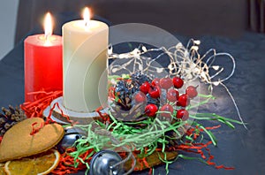 Christmas composition: red and white burning candles on a festive table on a dark background. Gingerbread, tinsel, festoon.