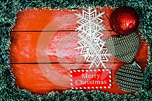 Christmas composition on red wooden board with Christmas garland and decorations. Creative composition with border and copy space