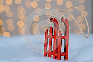 Christmas composition with red wooden Santa Claus sleigh, fir cone and Xmas tree balls over blurred light background