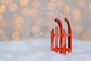 Christmas composition with red wooden Santa Claus sleigh, fir cone and Xmas tree balls over blurred light background