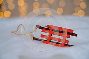 Christmas composition with red wooden Santa Claus sleigh, fir cone and Xmas tree balls over blurred light background